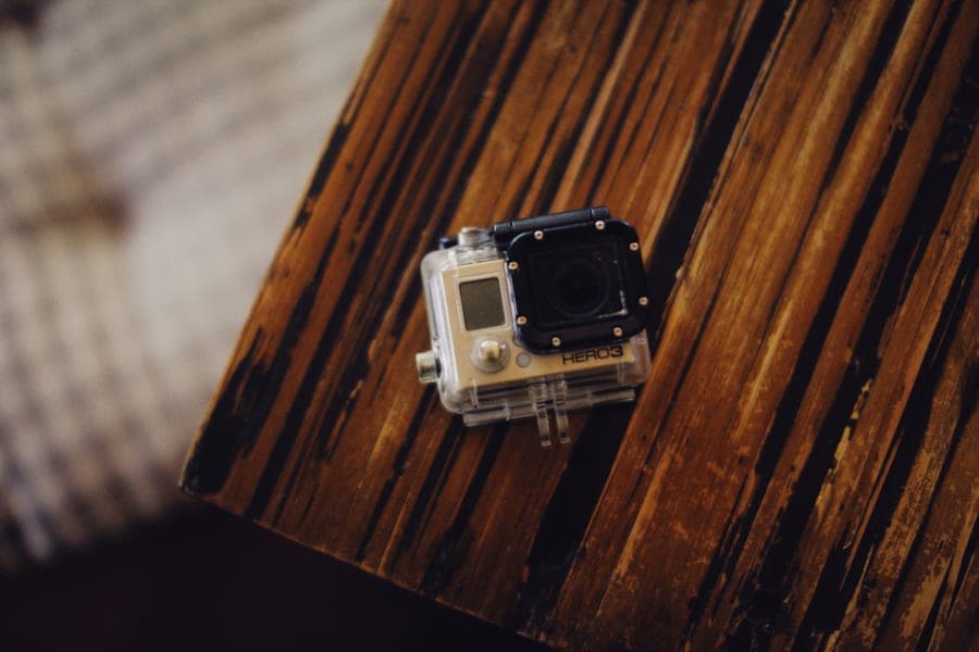 A compact action camera in a clear housing on a dark wooden table